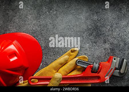 Big Monkey Wrench sur des gants de travail et casque de construction sur fond sombre Banque D'Images