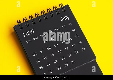 Calendrier de bureau noir et blanc de juillet 2025 sur fond de couverture jaune. Concept de calendrier. Banque D'Images