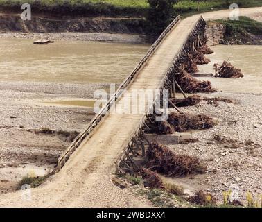 Comté de Vrancea, Roumanie, env. 1975. Vue sur la vallée de la rivière Putna, avec le vieux pont en bois au village de Poduri. Banque D'Images