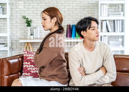 Photo d'un homme et d'une fille asiatiques ressentis agissant comme se disputant un couple et ne se parlant pas, assis ensemble sur un canapé à la maison Banque D'Images