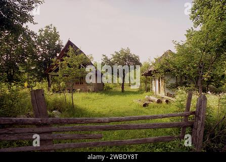 Comté de Vrancea, Roumanie, environ 2001. Une vieille petite maison et une cabane en bois en cours de construction sur une propriété rurale. Banque D'Images