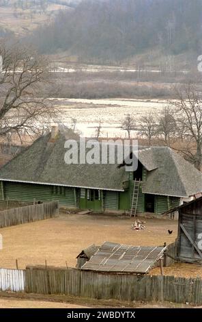 Comté de Vrancea, Roumanie, env. 1992. Une ferme rurale traditionnelle, avec une maison en bois avec cour fermée, une écurie attachée et fenaison. Banque D'Images