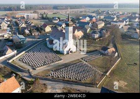 Ralbitz, Allemagne. 09 janvier 2024. Des croix tombales se dressent dans un cimetière en face de l'église de la paroisse de 'Sankt Katharina' Ralbitz (vue aérienne avec un drone). Crédit : Sebastian Kahnert/dpa/Alamy Live News Banque D'Images