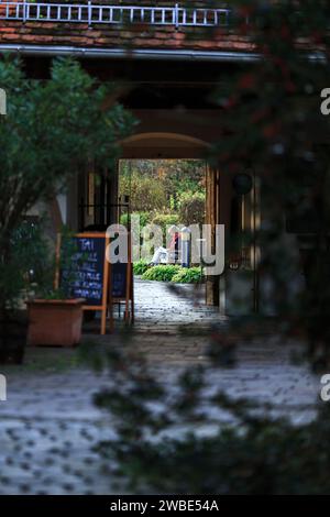 Une femme lisant son livre dans un jardin. Il est situé dans une ruelle à Bad Radkersburg Autriche. Vue à travers une porte Banque D'Images