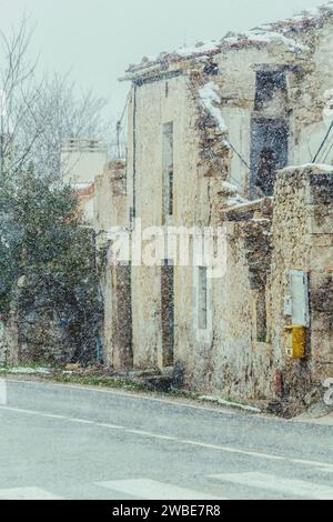 Détail d'une maison rurale à côté de la route à moitié détruite couverte par la neige, photo verticale Banque D'Images