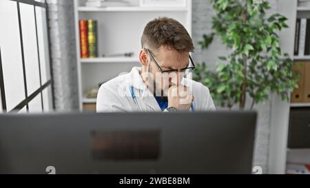 Beau jeune homme hispanique, un médecin, assis à sa clinique, travaillant sur le diagnostic en ligne via ordinateur, tout en se sentant malade, toussant, luttant contre la grippe. po Banque D'Images