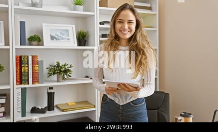 Portrait d'une jeune femme hispanique confiante et souriante au travail, une belle femme d'affaires prospère tenant des documents au bureau Banque D'Images