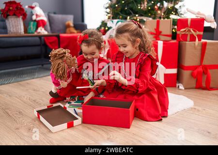 Adorables filles célébrant noël déballer crayons de cadeau à la maison Banque D'Images