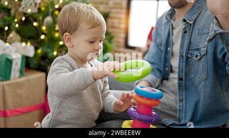 Père et fils célébrant noël en jouant avec des jouets à la maison Banque D'Images