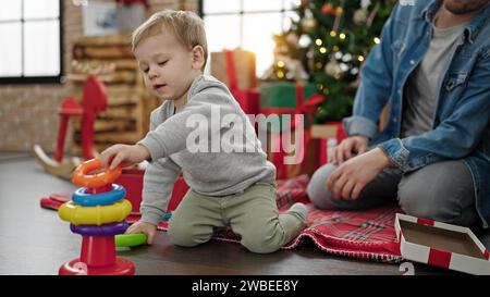 Père et fils célébrant noël en jouant avec des jouets à la maison Banque D'Images