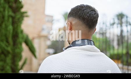 Vue arrière d'un homme à la mode avec une oreille percée sur une rue de la ville, capturant une ambiance urbaine et élégante. Banque D'Images