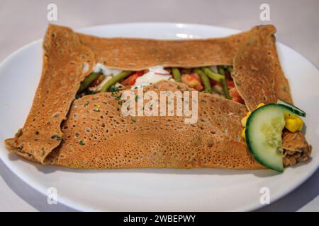 Crêpe végétarienne de sarrasin avec haricots verts, tomates, champignons et fromage dans un restaurant winstub à Colmar, en France, village de la route des vins d'Alsace Banque D'Images