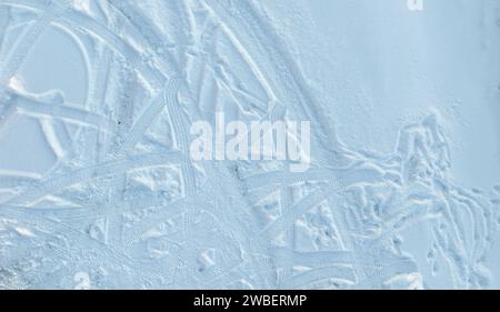 Une vue aérienne des traces de pneus de voiture sur la neige fraîche dans le stationnement Banque D'Images