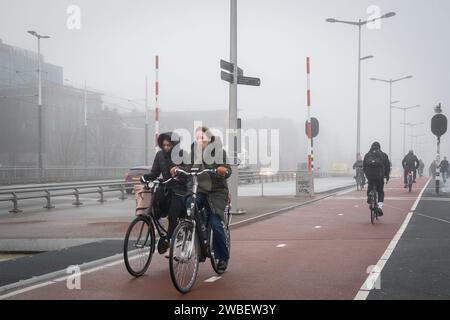 Les navetteurs font du vélo pour travailler dans les voies cyclables par un matin brumeux froid près de la gare centrale d'Amsterdam Banque D'Images