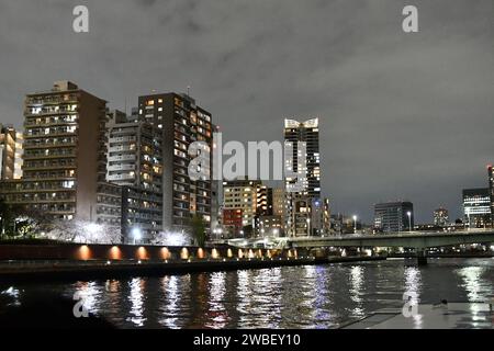 Une vue aérienne imprenable sur une ville animée la nuit, avec des bâtiments illuminés au bord de la rivière créant une atmosphère vibrante Banque D'Images