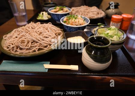 Un délicieux dîner de nouilles et légumes de style asiatique servi sur une table avec deux tasses de boissons et de sauces Banque D'Images