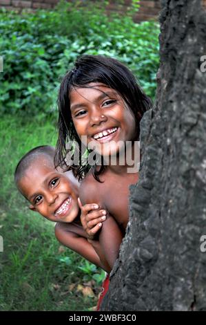 Portrait de deux enfants jouant à cache-cache dans les bidonvilles de rayer bazar. Bangladesh. Banque D'Images