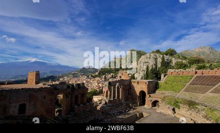 Ancien amphithéâtre avec des ruines devant une silhouette de ville et l'Etna en arrière-plan, Taormina, Sicile orientale, Sicile, Italie Banque D'Images