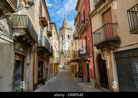 Une ruelle étroite avec des maisons colorées et une tour d'église à la fin, Novara di Sicilia, Sicile, Italie Banque D'Images