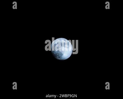 Un beau ciel nocturne illuminé par la pleine lune, avec un avion au premier plan volant devant Banque D'Images