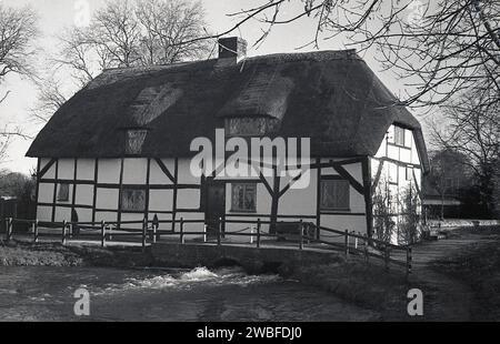 Années 1960, ancien bâtiment historique à ossature de bois de chaume à Alresford, sur la rivière Alre, un moulin à fouler, datant du 13e siècle. Un moulin à fouler a été utilisé pour battre le tissu de laine humide après qu'il a été tissé, pour le faire rétrécir et resserrer. Cet ancien moulin à eau ou fulling a été construit pour la première fois vers AD1331 et a été sauvé de la démolition en 1951. Le fulling Mills et le fulling font partie du processus de fabrication du tissu et impliquent le nettoyage et le broyage du tissu tissé pour produire un matériau plus épais et plus dense, et donc plus chaud et hydrofuge. Banque D'Images