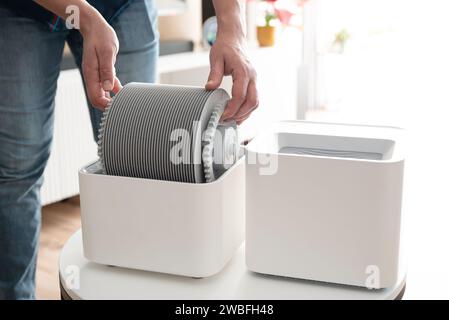 Humidificateur d'air moderne dans le salon. Des conditions de vie confortables. Homme changeant le filtre Banque D'Images