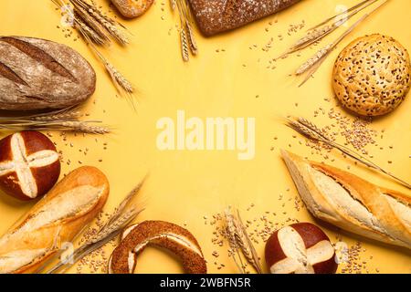 Cadre fait de différents types de pain et épis de blé sur fond jaune Banque D'Images