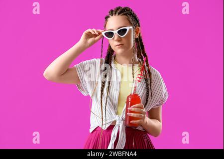 Jeune femme avec des dreadlocks et boire sur fond rose Banque D'Images