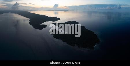 Le lever du soleil illumine les mers calmes autour des îles de Gam et Yangeffo à Raja Ampat, en Indonésie. Cette région est surtout connue pour sa grande biodiversité. Banque D'Images