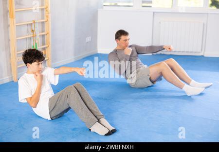 Garçon adolescent et homme d'âge moyen entraînant des coups de poing couchés en position de presse Banque D'Images