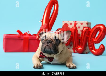 Mignon bulldog français avec boîtes cadeaux et ballon en forme de mot AMOUR sur fond bleu. Fête de la Saint-Valentin Banque D'Images