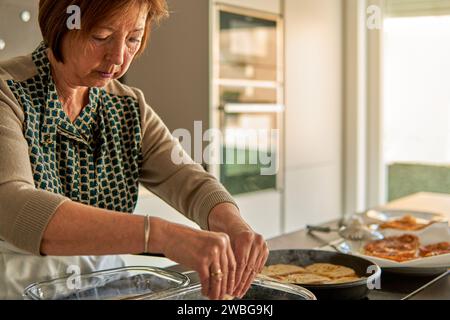 Grand-mère trempage du pain dans le lait et l'œuf pour la recette de torrijas. Banque D'Images