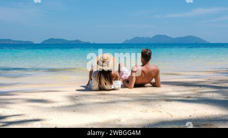 Un jeune couple d’hommes et de femmes assis sur une plage tropicale lors de vacances de luxe en Thaïlande, couple diversifié allongé sur la plage de Koh Wai I. Banque D'Images