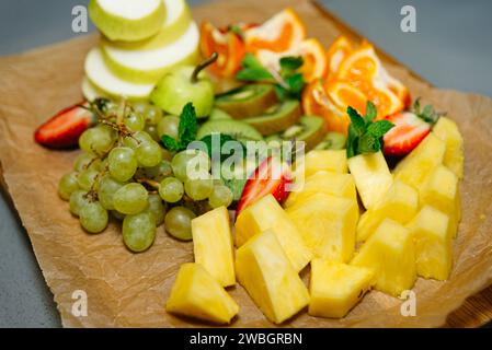Une sélection vibrante de fruits frais, y compris des raisins, des fraises, de l'ananas et du kiwi, magnifiquement arrangé pour une collation ou une fête. Banque D'Images