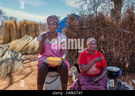 Famille africaine , heure du déjeuner dans le village, cabane, cuisine en plein air , camp de travail coupant l'herbe de chaume , manger pap pour la pause déjeuner, de manière traditionnelle, Banque D'Images