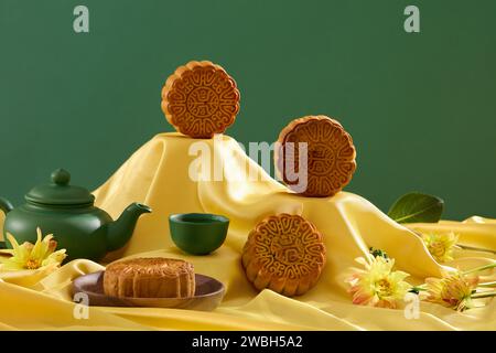 Gâteaux de lune de forme ronde placés sur un tissu jaune avec un service à thé de couleur verte. Délicieux festival traditionnel chinois. Fête de la mi-automne de la nourriture lune ca Banque D'Images