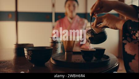Femme versant le thé japonais traditionnel avec kimono, théière et se détendre avec pleine conscience, respect et service. Fille au salon de thé calme avec boisson matcha dedans Banque D'Images