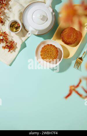 Délicieux gâteaux de lune cuits au four décorés avec un service à thé placé sur une serviette blanche. Une branche de fleur comme premier plan. Zone vide pour montrer votre produit ou ajouter tex Banque D'Images