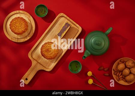 Les gâteaux de lune traditionnels, les noix d'amande et les noix sont placés sur des assiettes en bois et une planche à découper. Les gâteaux de lune ont beaucoup de saveurs différentes et sont des incréas Banque D'Images