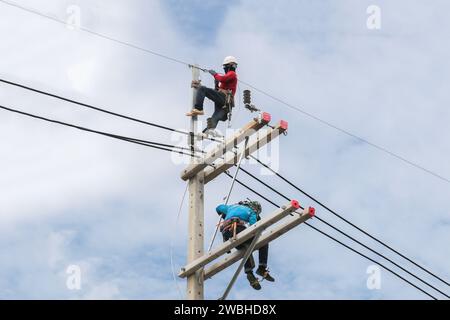 Électriciens travaillant sur les câbles de connexion des colonnes de service Banque D'Images