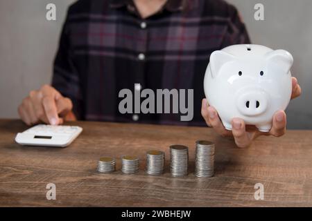 Main masculine insérant des pièces dans le porcelet pour collecter de l'argent et le concept de finance. Banque D'Images