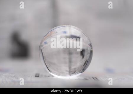 Un globe de verre révèle les lettres à l'intérieur, avec un journal en arrière-plan. Banque D'Images