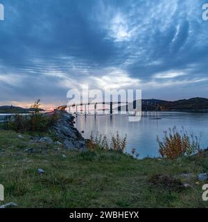 Le pont de Sommarøy, il courbe majestueusement et traverse l'Atlantique sur la côte de Troms, Norvège. plantes colorées automnales sur le rivage de l'océan Banque D'Images