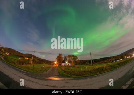 Belles aurores boréales vertes sur un fjord et une maison sur l'île de Kvaloya près de Tromsø. danser des lumières polaires au-dessus d'une montagne, aurora borealis Banque D'Images