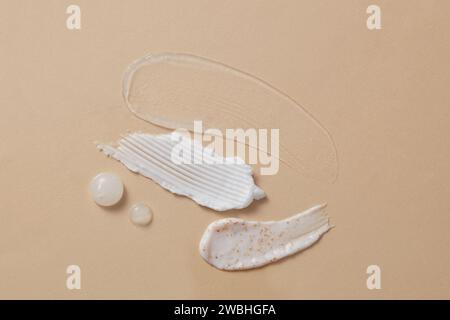 Vue de dessus de différentes textures cosmétiques de gel transparent, gommages, essence et crème pour le corps décorées sur fond beige. Scène pour la publicité et br Banque D'Images