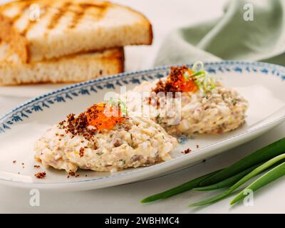 Poisson apéritif forshmak - viande hachée de poisson de hareng, caviar décoré sur l'assiette. Plat traditionnel juif de cuisine vorschmack forshmak fait de filet de hareng comme plat indépendant sur fond de bois Banque D'Images