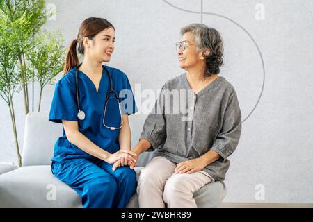 Jeune femme asiatique médecin ou infirmière soutient joyeusement le patient âgé, femme médecin thérapeute assis sur le canapé à l'hôpital avec le patient âgé pendant la médecine Banque D'Images