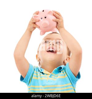 Garçon enfant, tirelire et heureux en studio avec la pensée, l'argent et les économies par fond blanc. Enfant, boîte ou jouet animal pour pièces de monnaie, argent et apprendre à Banque D'Images