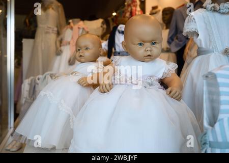 Un peu effrayante poupées aux yeux bleus dans des robes blanches affichées dans la vitrine, Porto, Portugal Banque D'Images