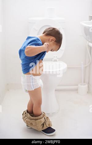 Garçon enfant, formation de pot et toilette avec la pensée, couche et pantalon sur le sol pour l'apprentissage, le développement et le progrès. Enfant, maison familiale et salle de bains Banque D'Images